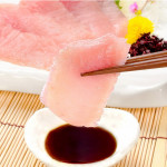 image of chopsticks dipping sashimi into soy sauce